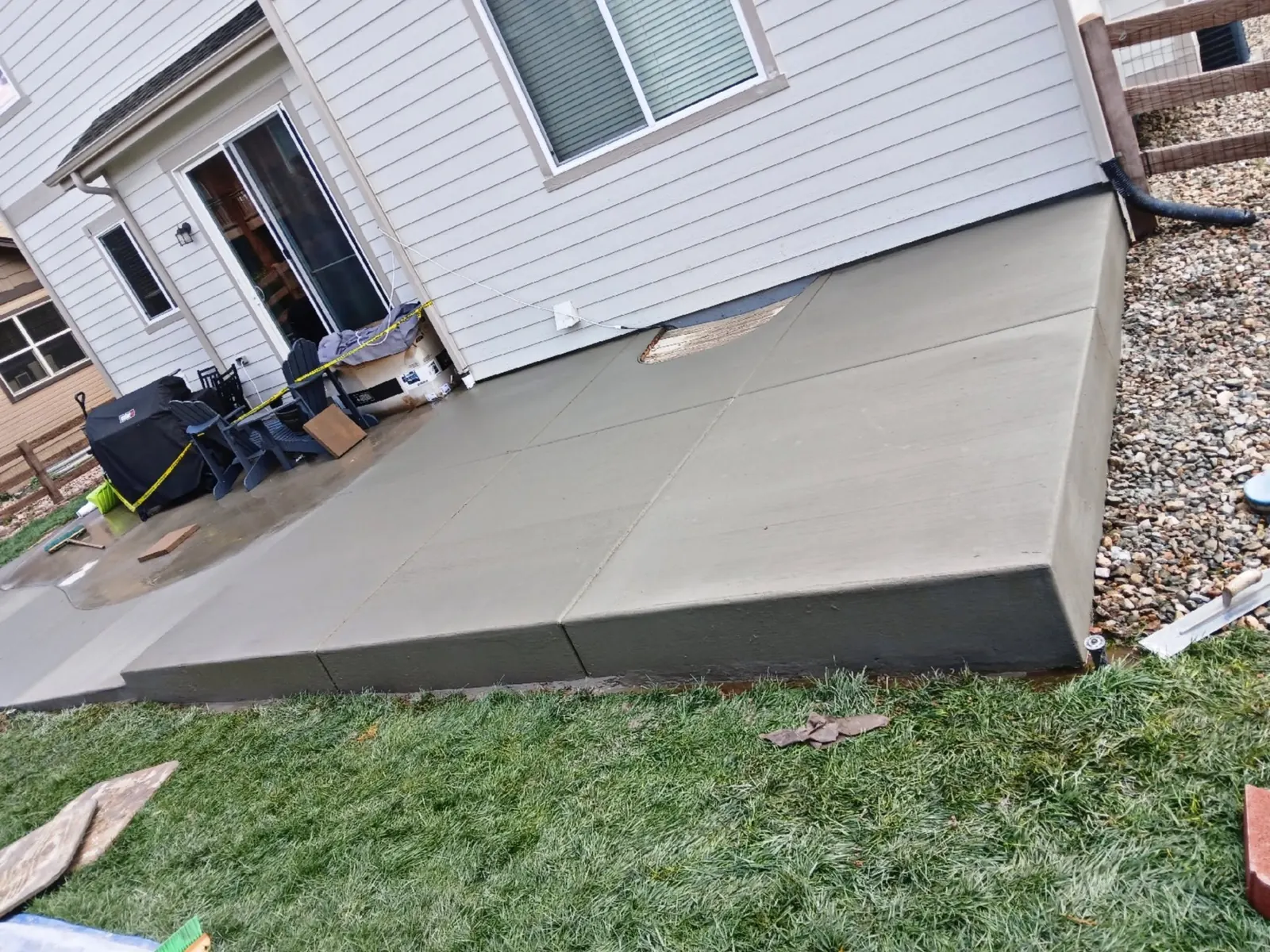 The same patio finished — forms stripped, edges tooled, and a clean raised slab edge above the lawn.