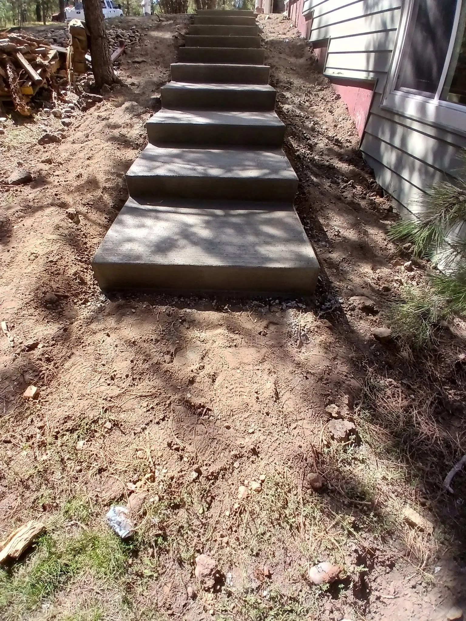 The same flight finished — poured concrete steps with even risers running up the slope beside the house.